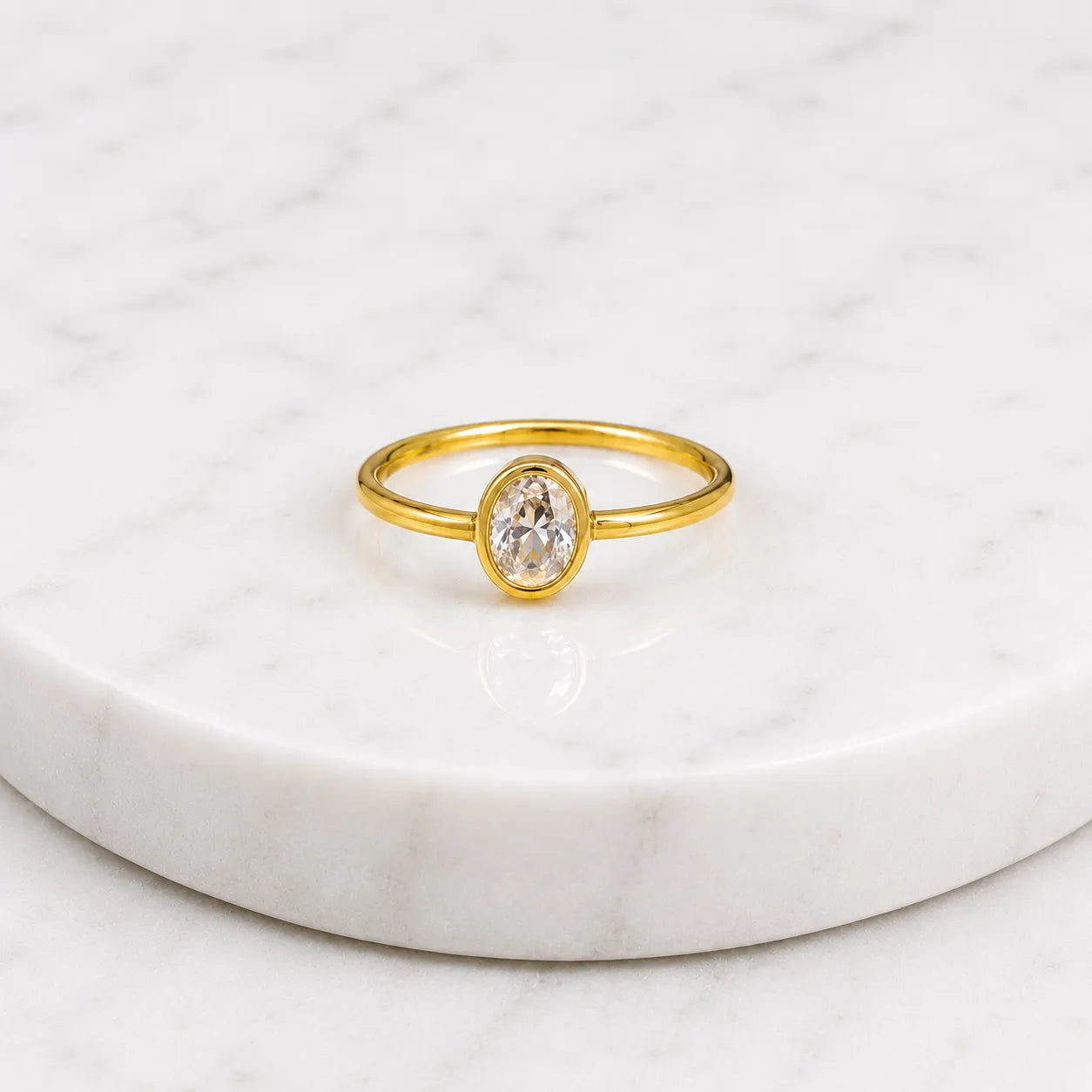 Gold ring with a diamond on a white marble surface