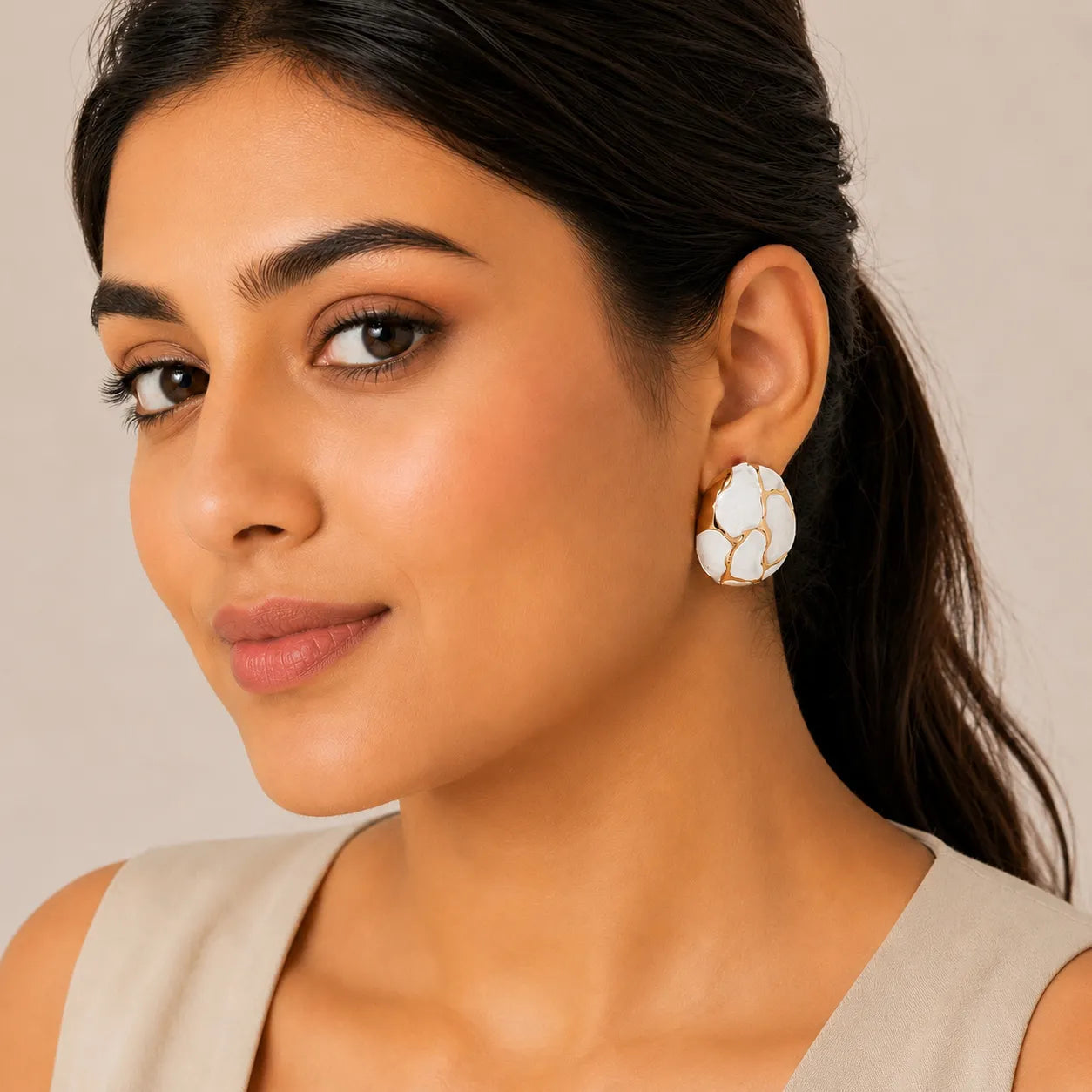 Woman wearing a pair of white floral earrings against a neutral background