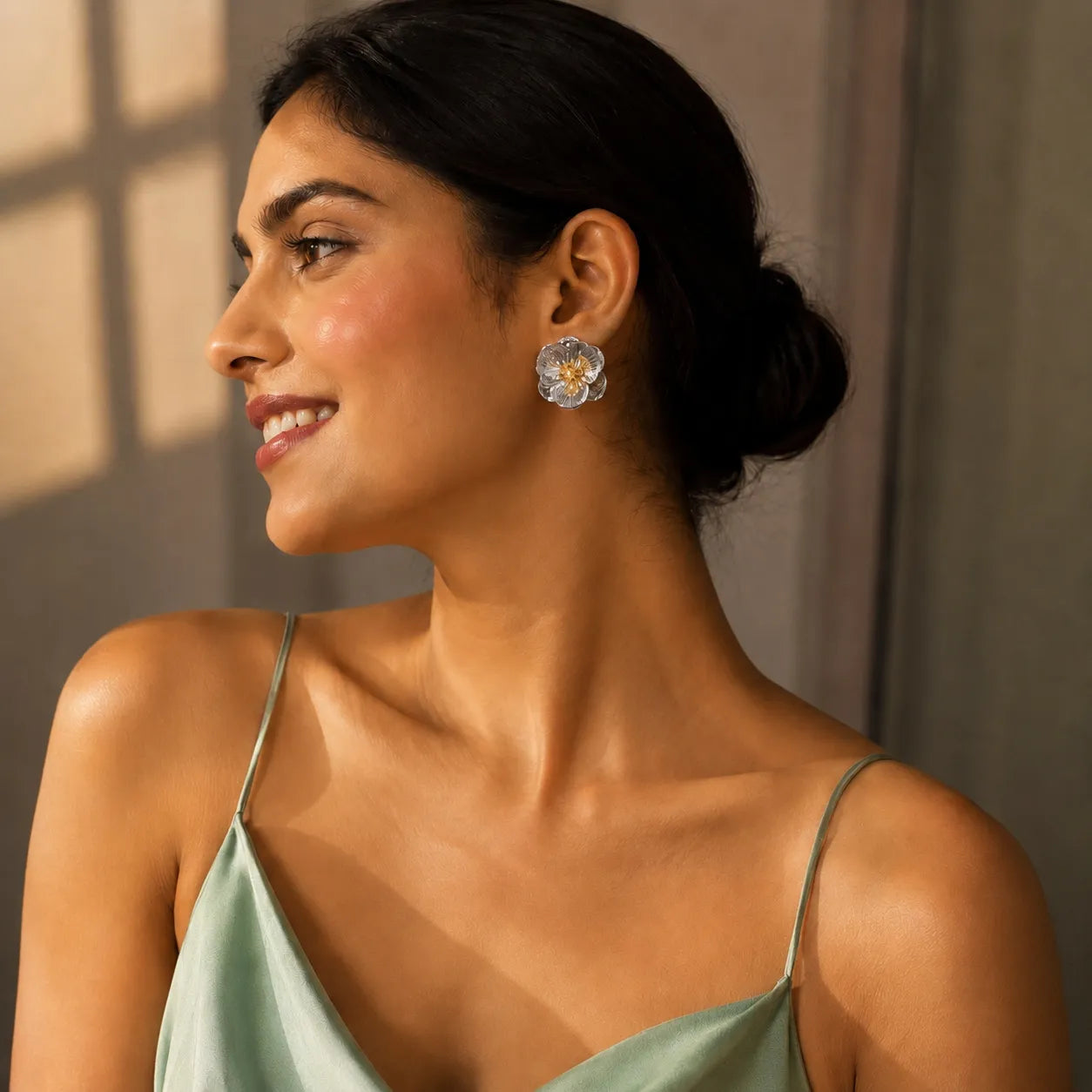 Woman wearing a light green dress and floral earrings in a warm setting