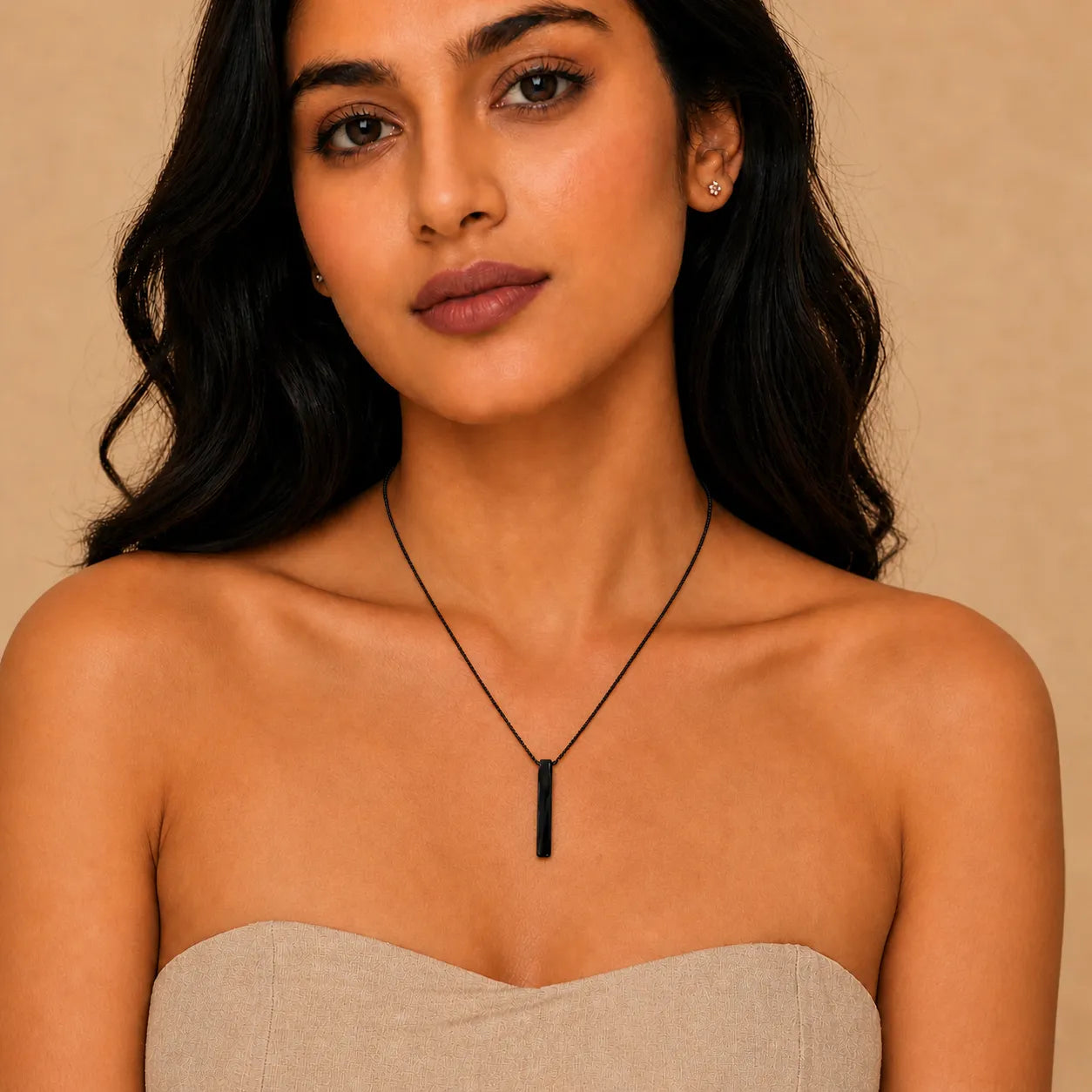 Woman wearing a black necklace against a beige background