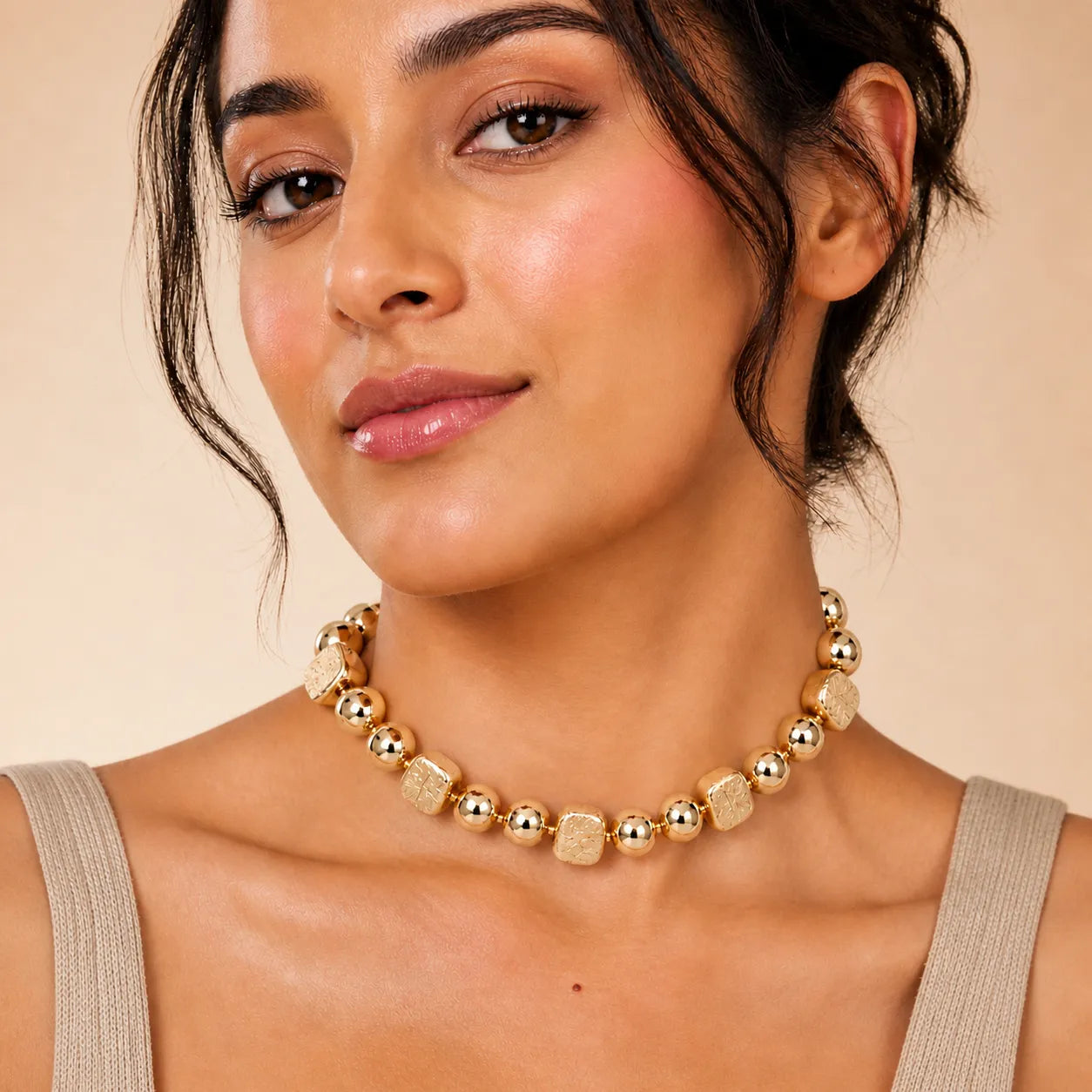 Woman wearing a gold necklace against a beige background