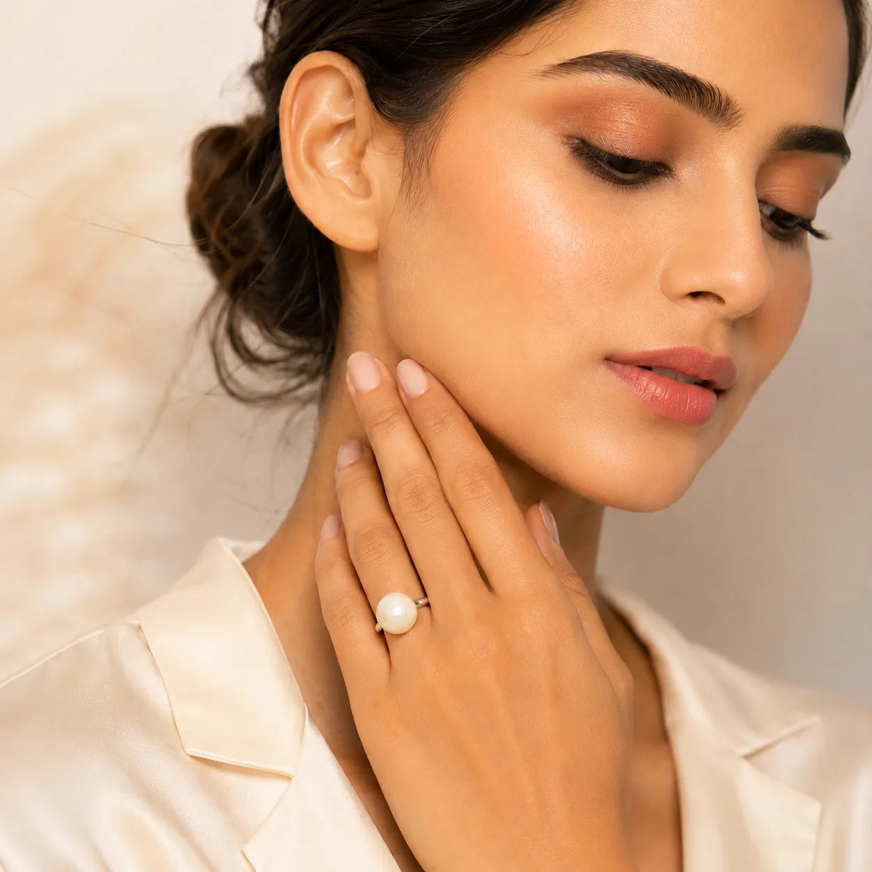 Woman wearing a pearl ring with a neutral background