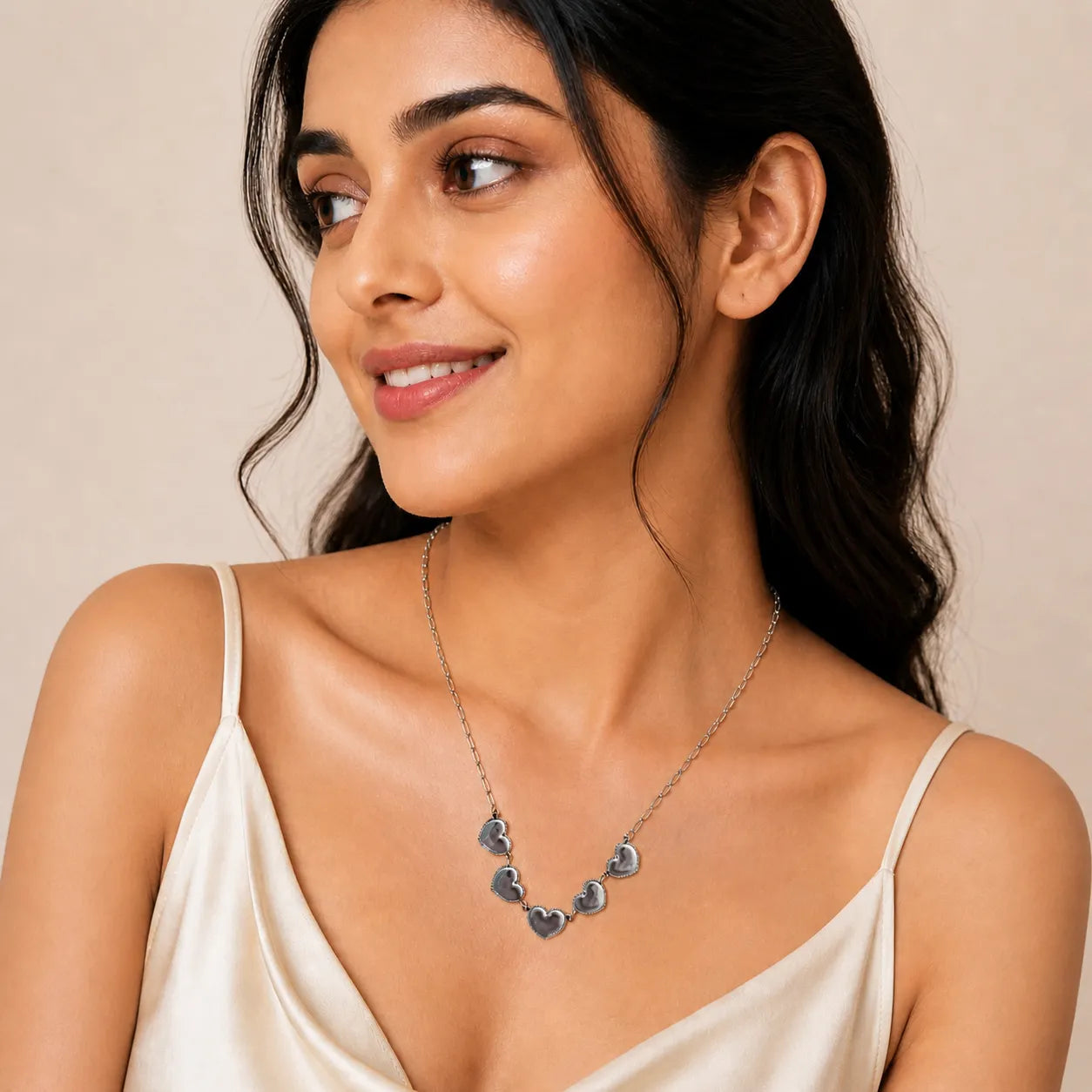 Woman wearing a delicate necklace against a neutral background