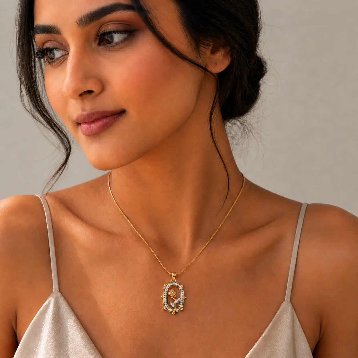 Woman wearing a gold necklace with a pendant against a neutral background