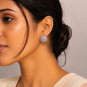 Close-up of a woman wearing sparkling silver earrings against a neutral background
