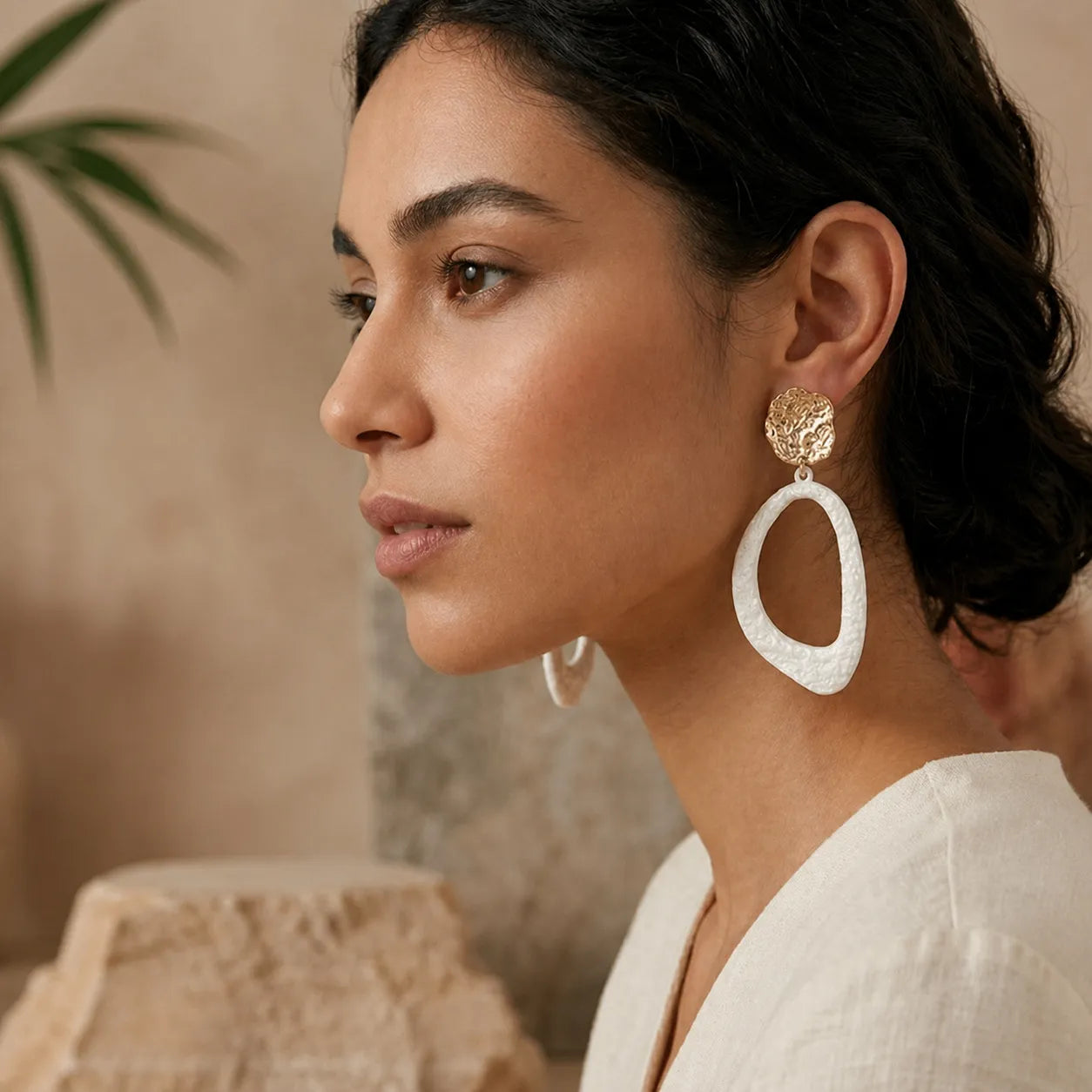 Woman wearing large hoop earrings with a neutral background