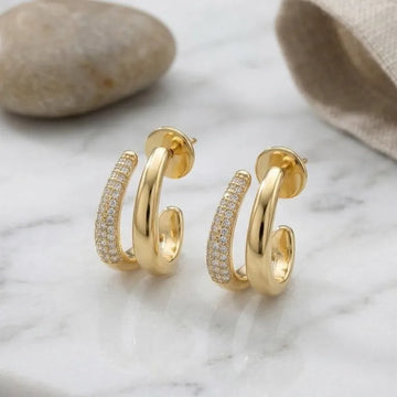 Gold hoop earrings with diamond accents on a marble surface.