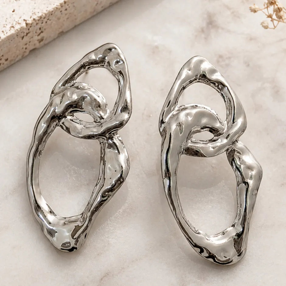 Pair of silver earrings on a light marble surface