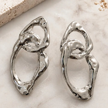 Pair of silver earrings on a light marble surface