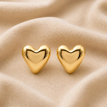 Gold heart-shaped earrings on a beige fabric background
