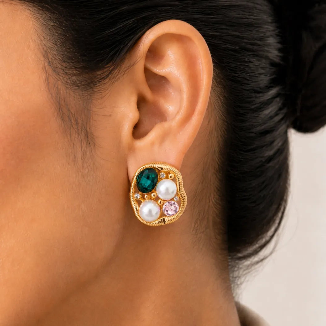 Close-up of an ear wearing a gold earring with colored gemstones.