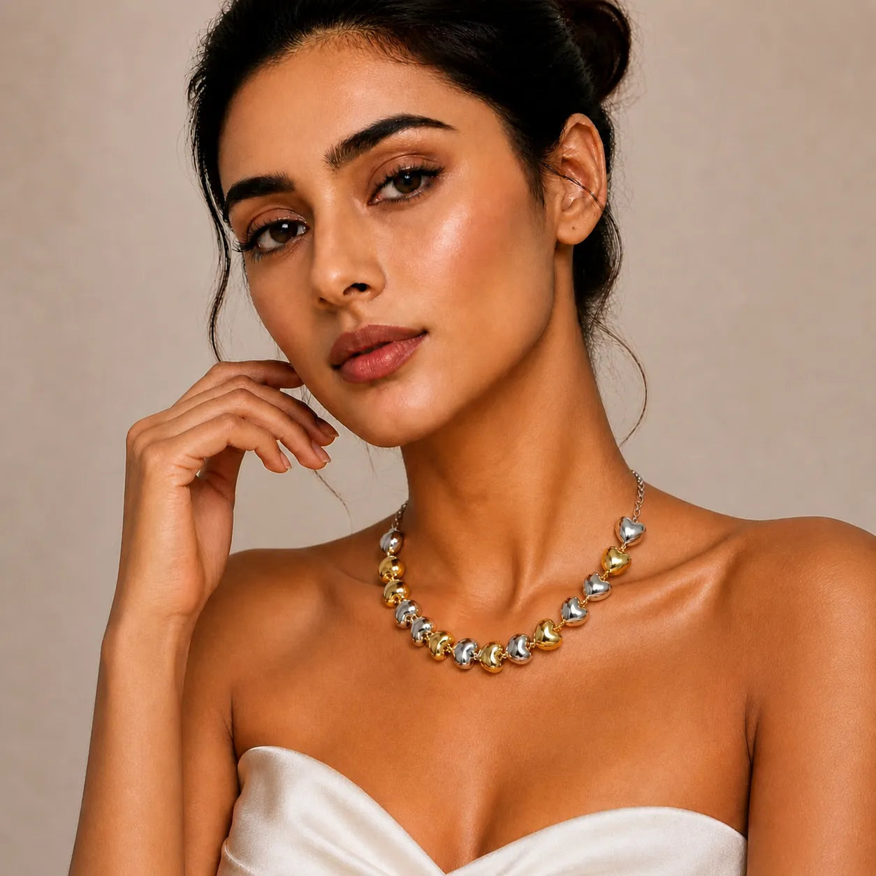 Woman wearing a gold and silver necklace against a beige background