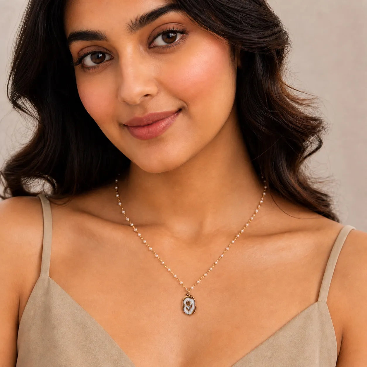 Woman wearing a necklace with a pendant against a neutral background