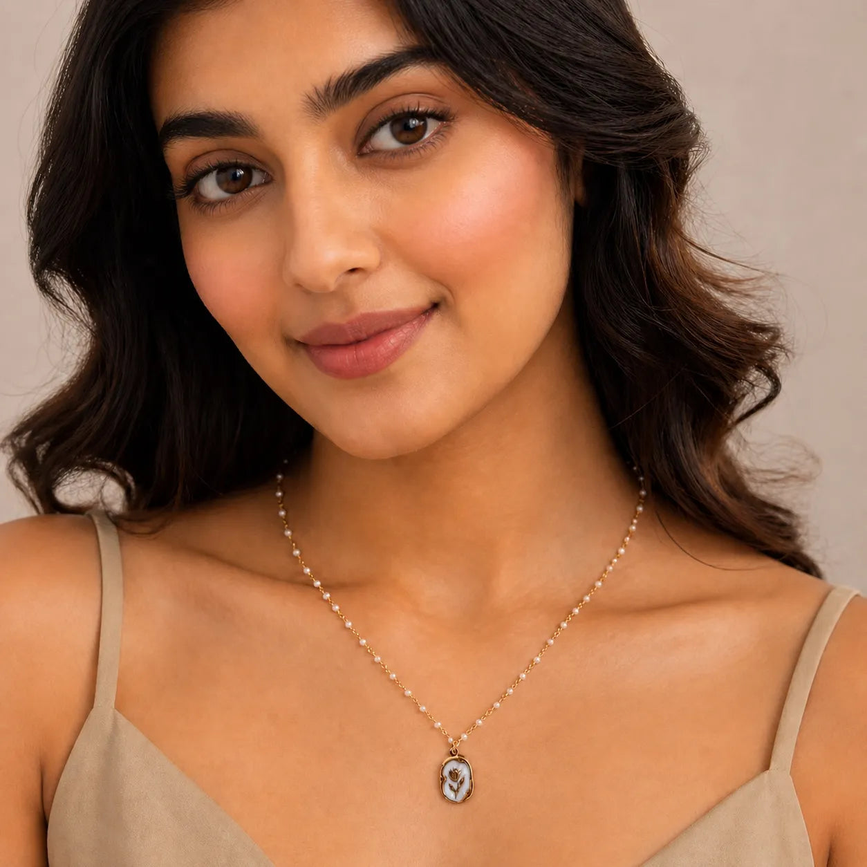 Woman wearing a necklace with a beige top against a neutral background