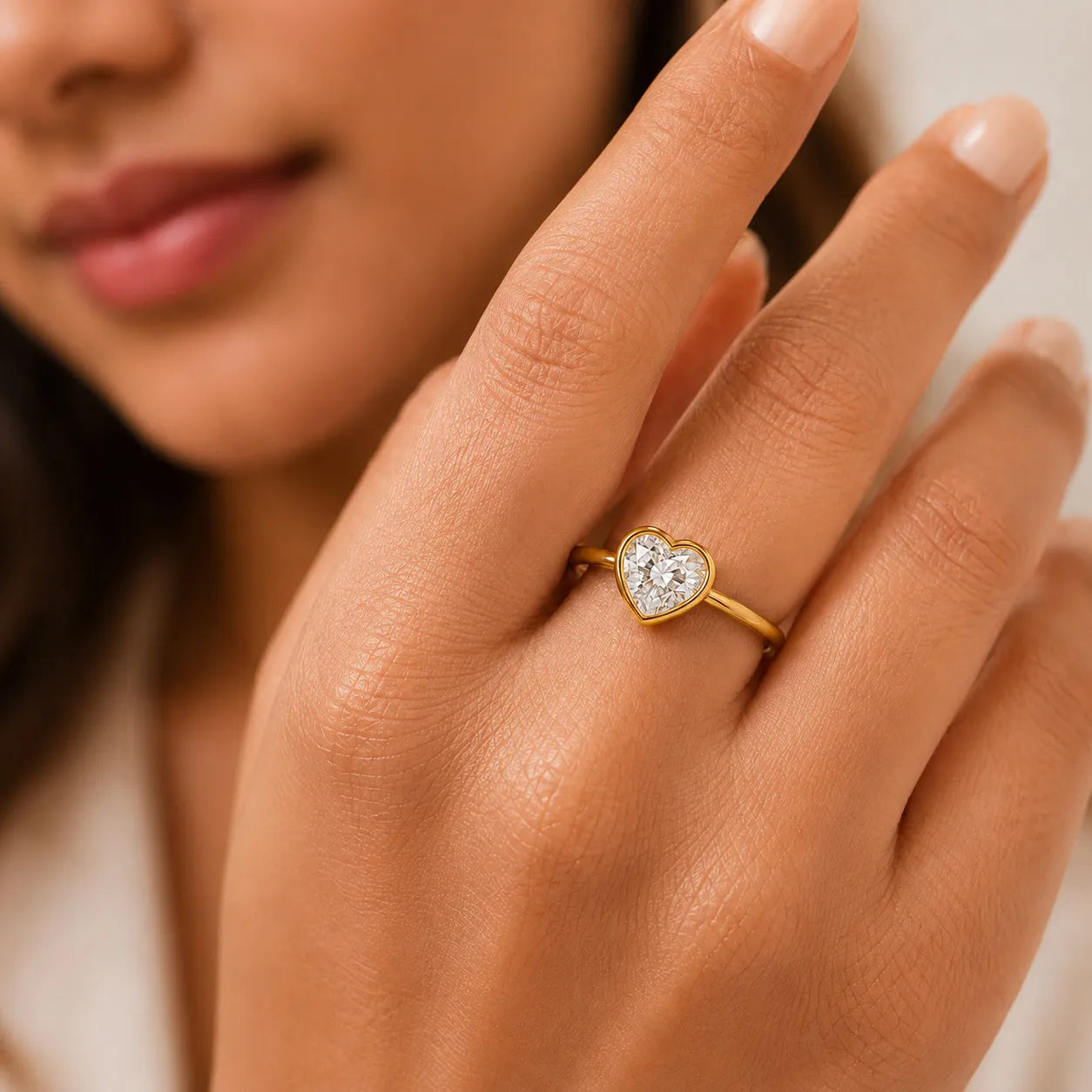 Close-up of a hand wearing a gold heart-shaped diamond ring.