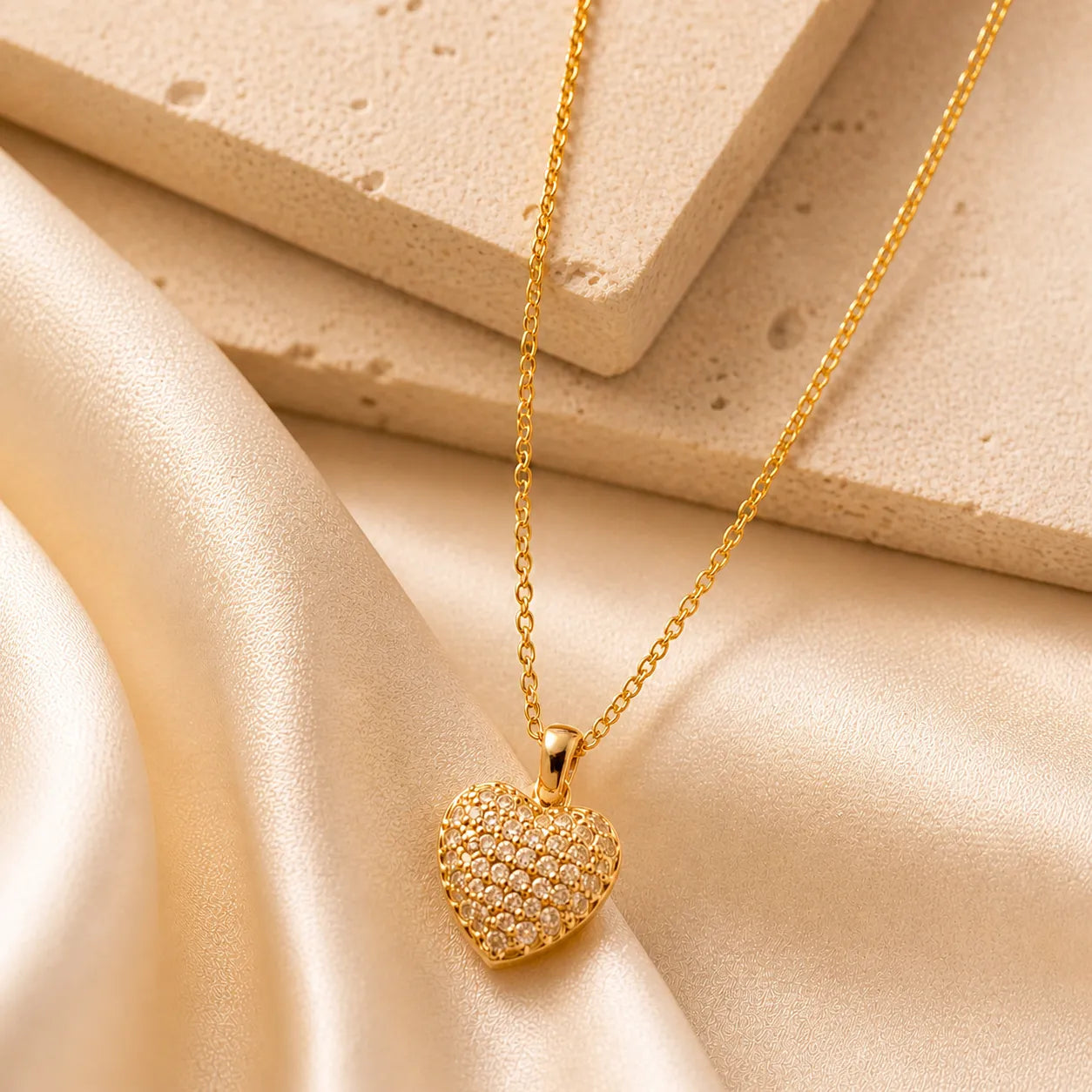 Gold heart-shaped pendant necklace on a beige fabric background