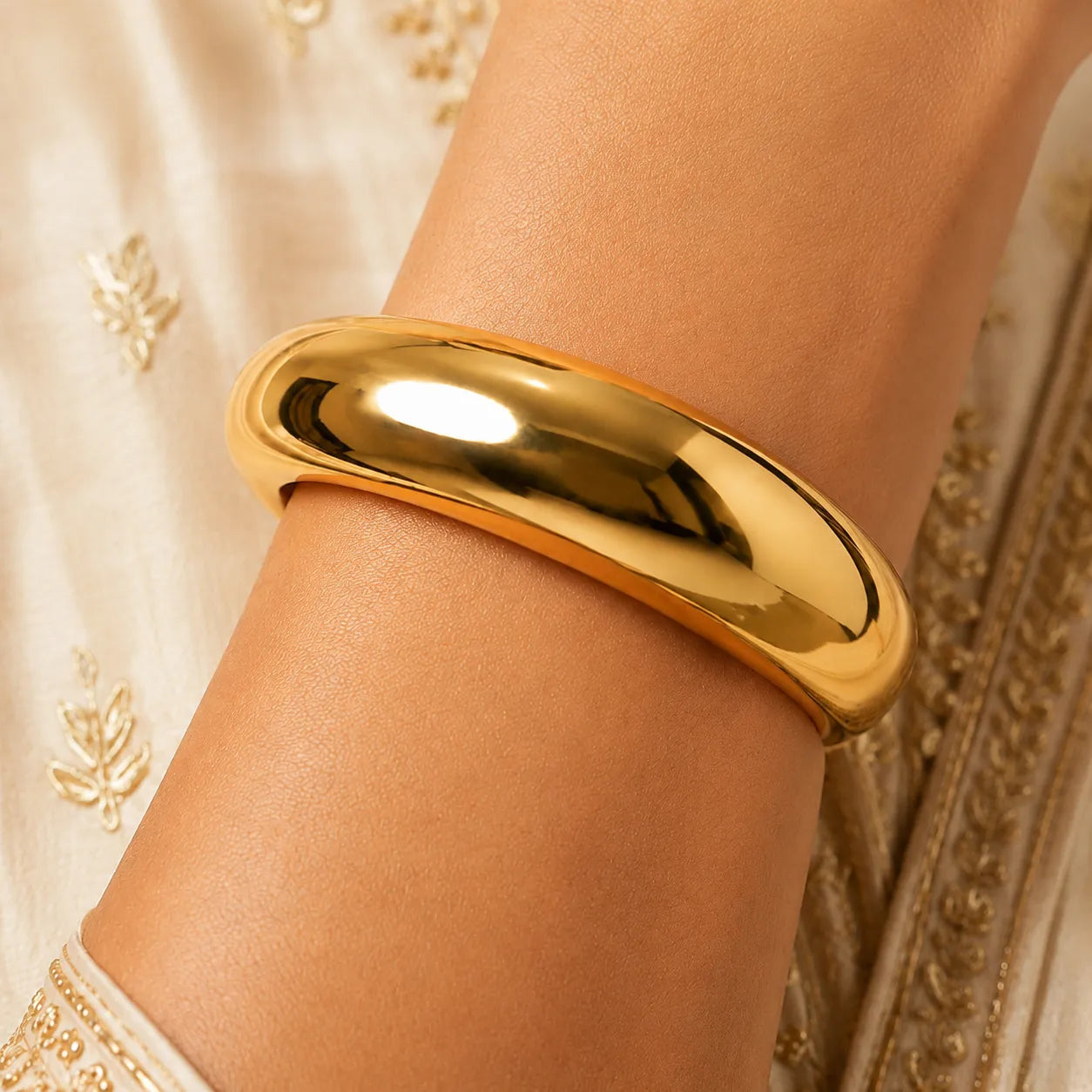 Gold bracelet on a wrist with a decorative background