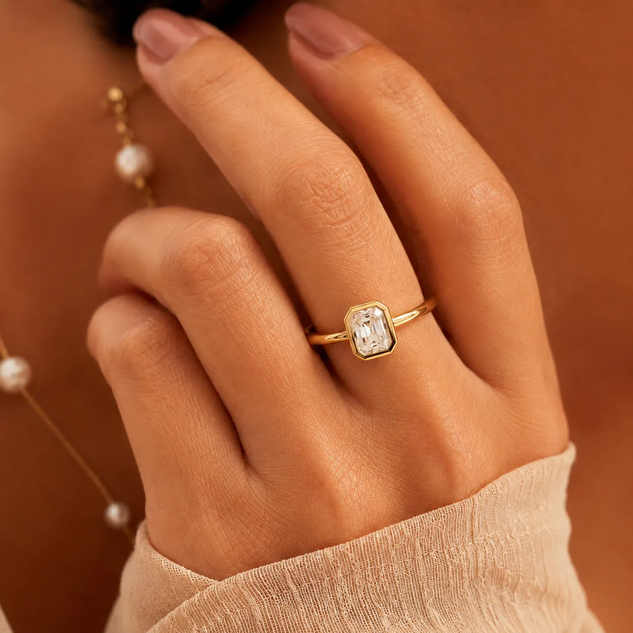 Close-up of a hand wearing a gold ring with a diamond on a brown background