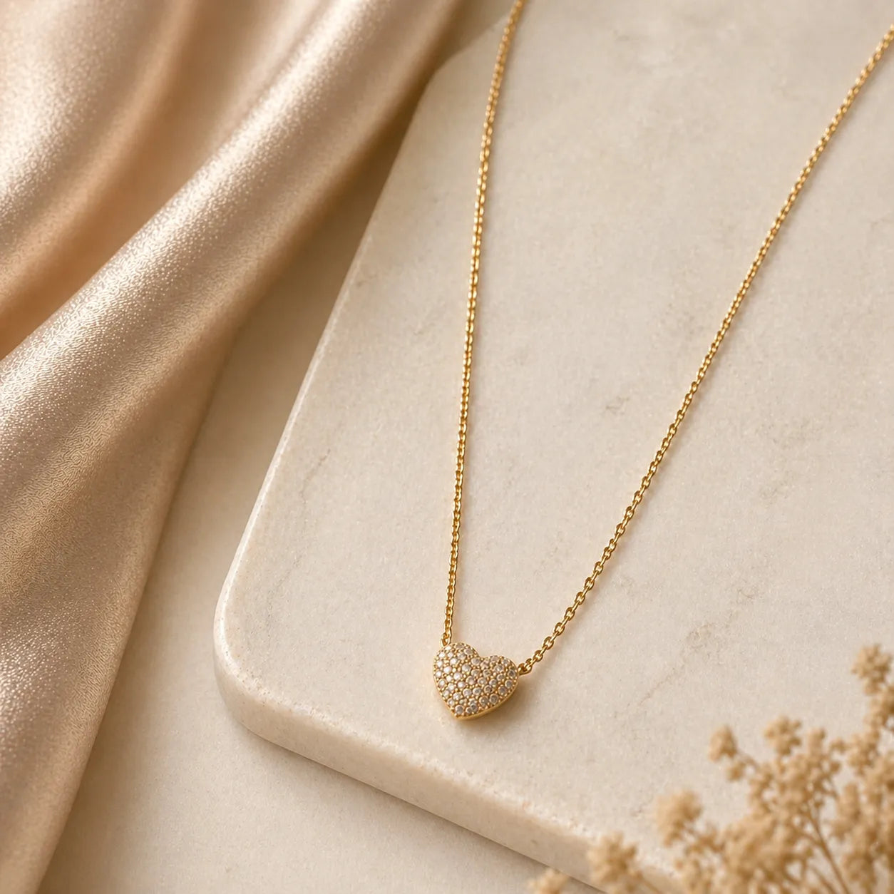 Gold necklace with a heart-shaped pendant on a beige fabric background