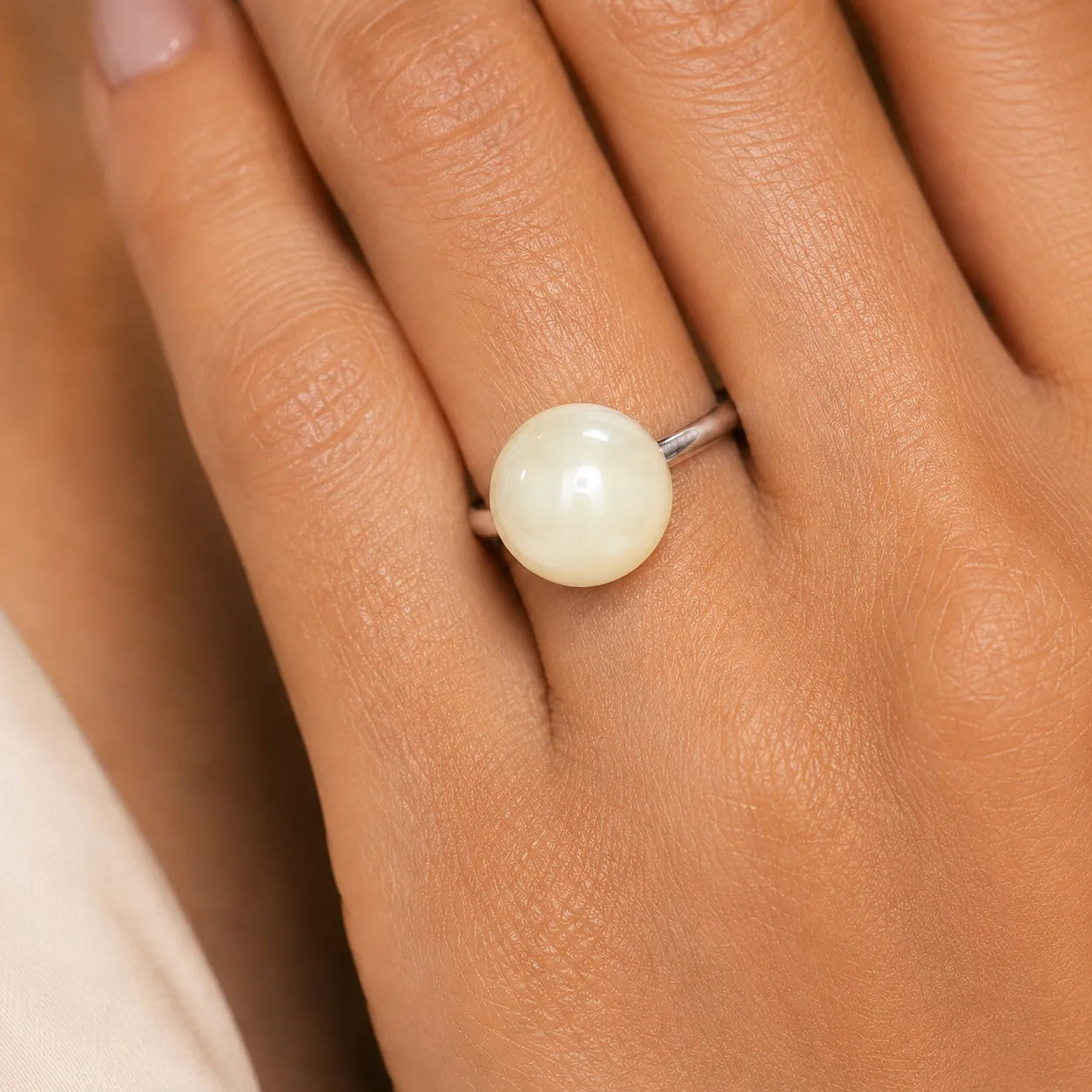 Pearl ring on a person's finger with a neutral background