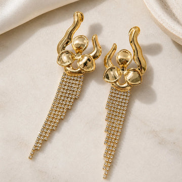 Gold earrings with intricate designs on a beige background