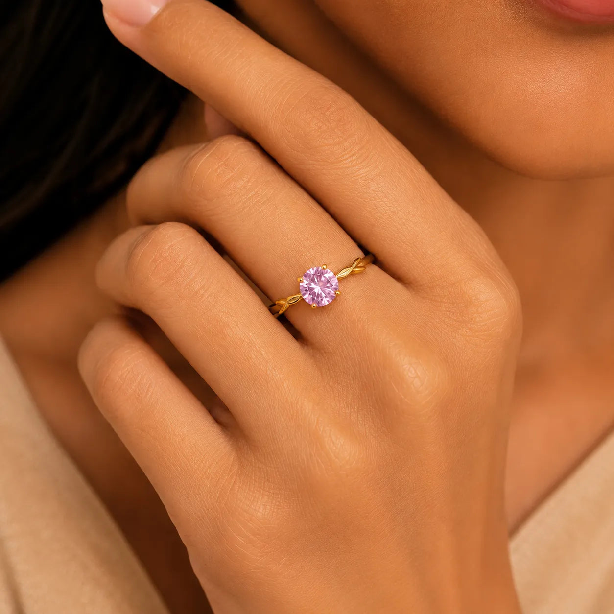 Close-up of a hand wearing a gold ring with a pink gemstone.