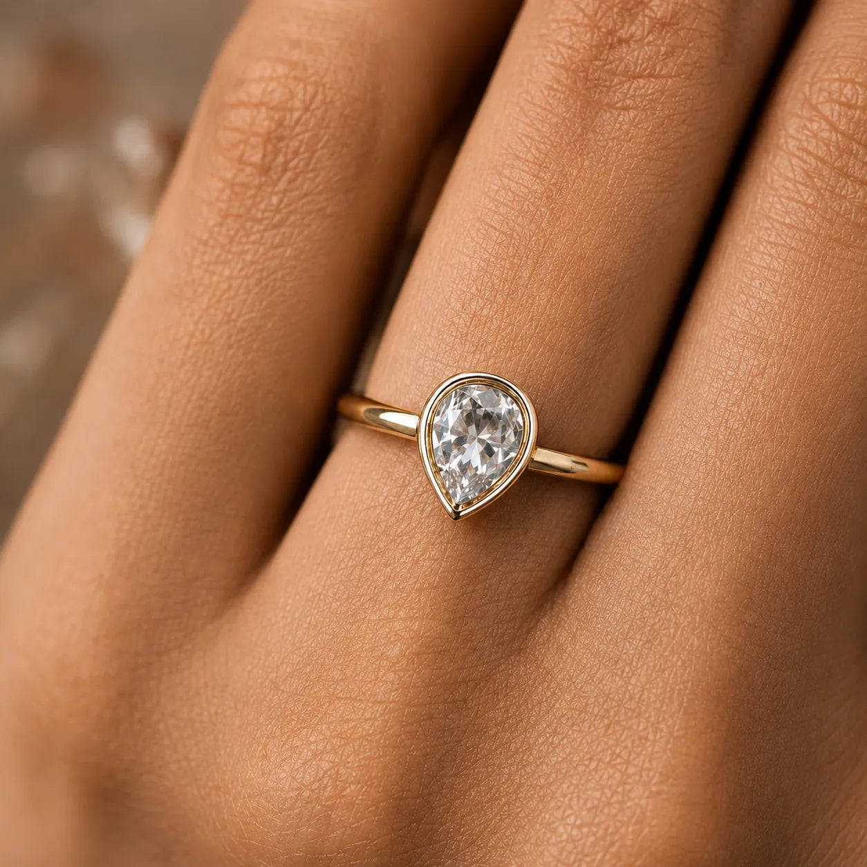 Gold ring with a teardrop-shaped diamond on a person's finger