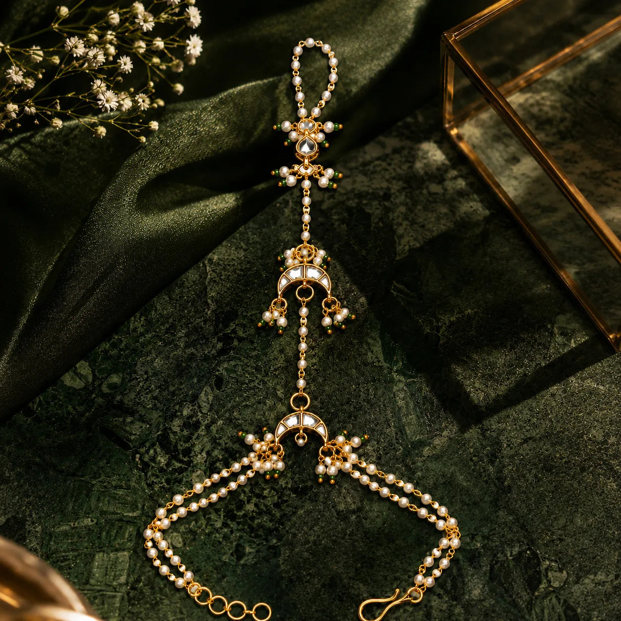 Delicate gold and pearl necklace on a dark green fabric background