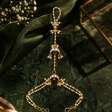 Delicate gold and pearl necklace on a dark green fabric background