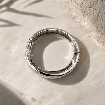 Silver ring on a light stone surface with natural light and shadow