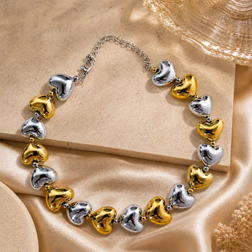 Bracelet with heart-shaped charms in gold and silver on a beige fabric background