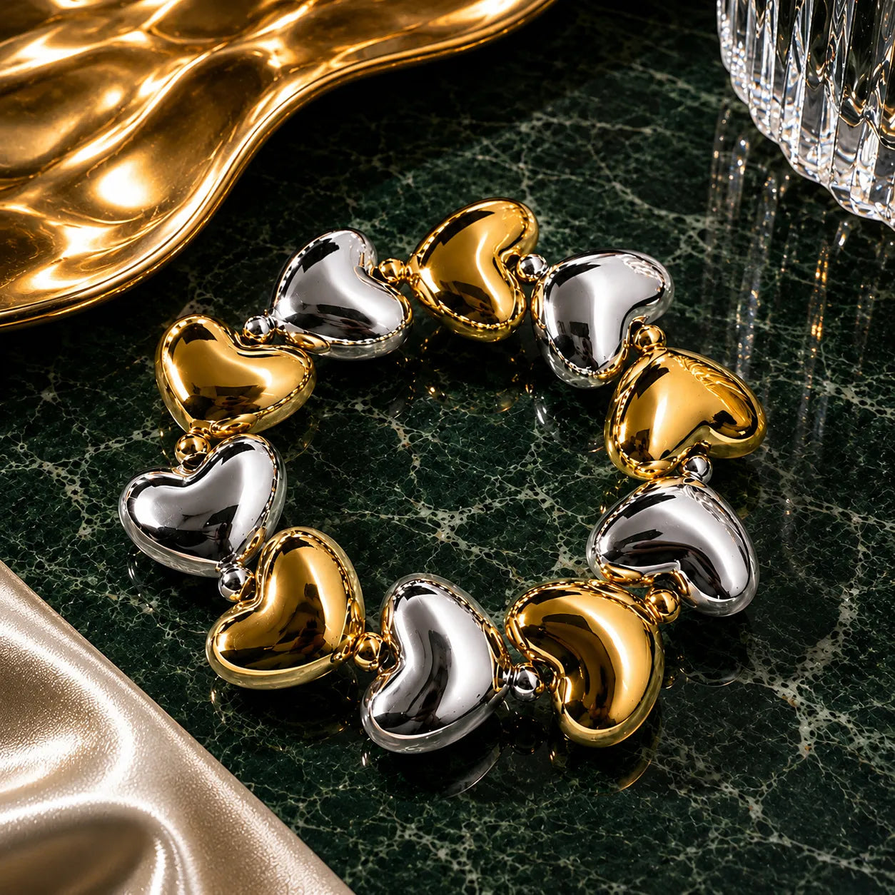 Bracelet with gold and silver heart-shaped charms on a dark marble surface.