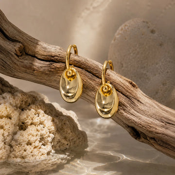 Gold earrings on a branch with a natural background