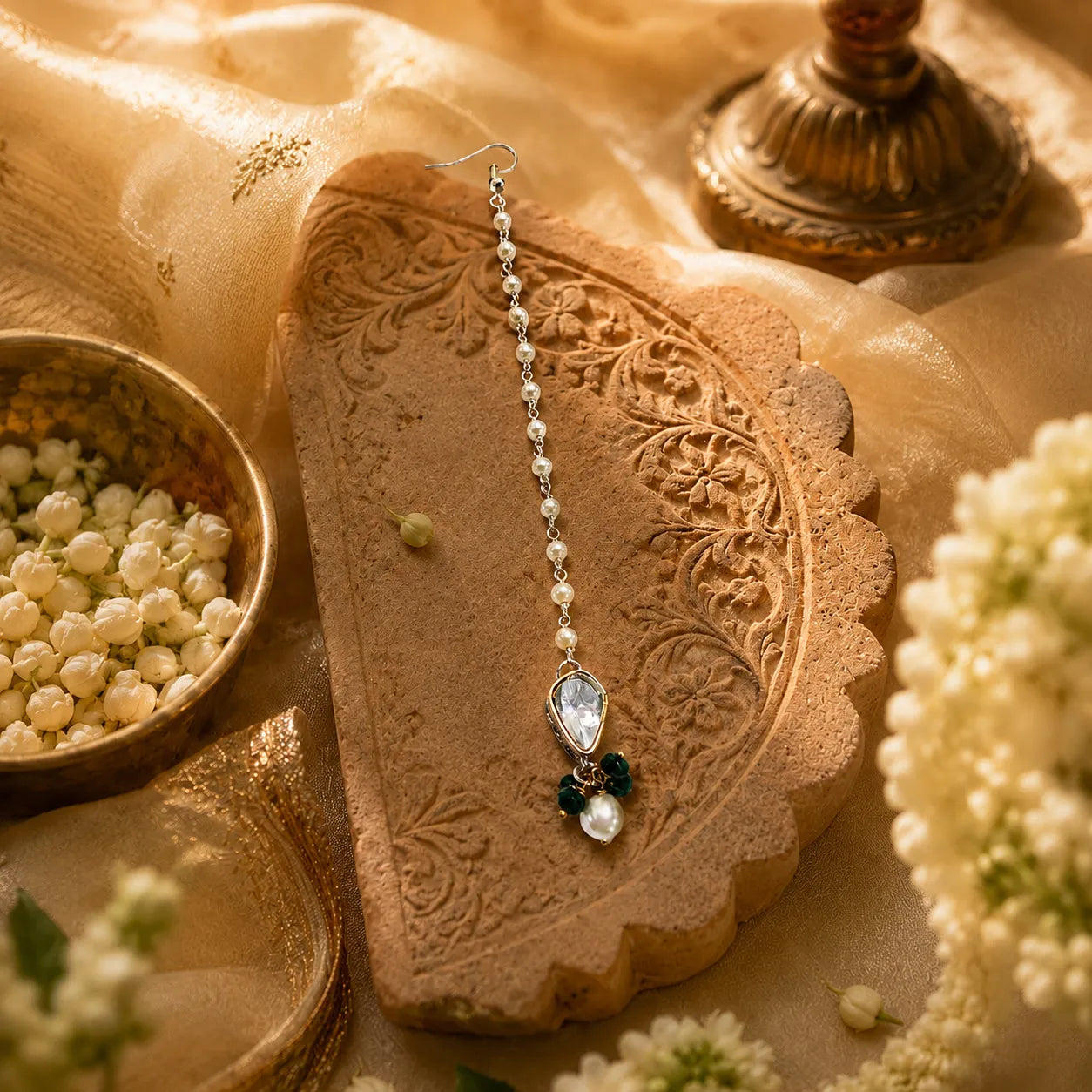 Pearl earring on a decorative stone with flowers and a bowl of pearls in the background