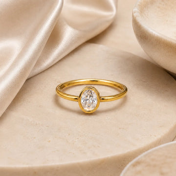 Gold ring with a clear gemstone on a beige fabric background