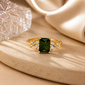 Gold ring with a green gemstone on a beige surface