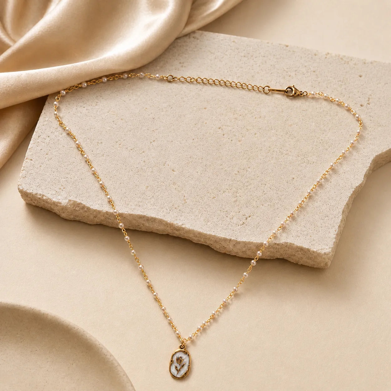 Gold necklace with a pendant on a beige stone surface