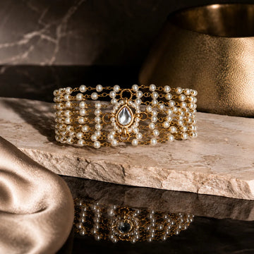 Gold and pearl bracelet on a wooden surface with a soft focus background