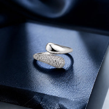 Silver ring with textured design on a blue fabric background