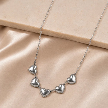 Silver heart-shaped necklace on a beige surface