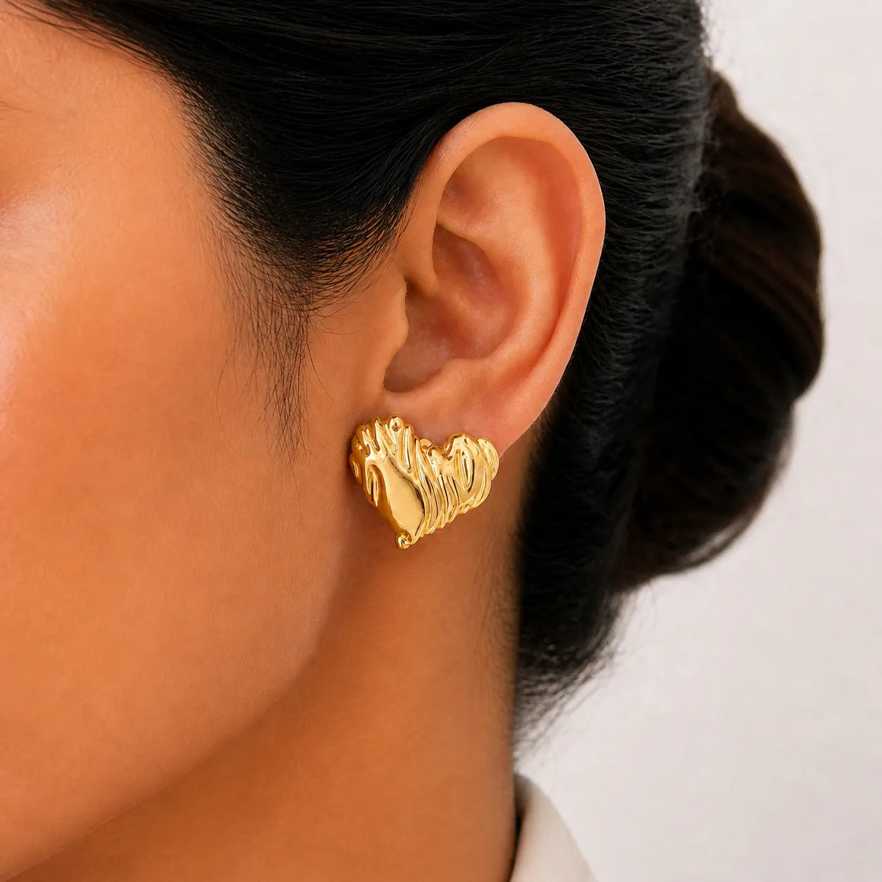 Gold earring worn by a person with a neutral background