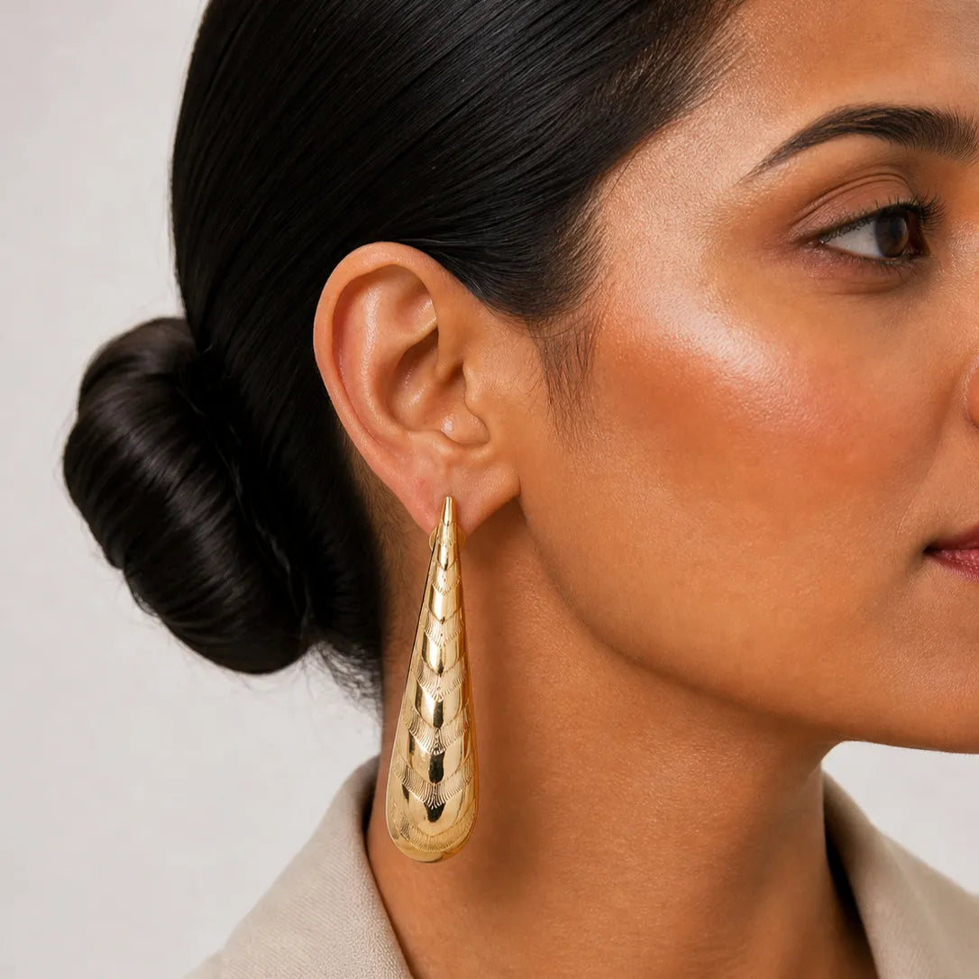 Close-up of a woman wearing a gold earring with a neutral background