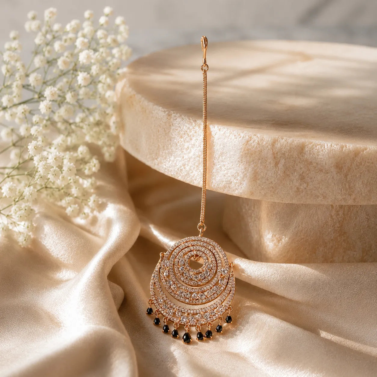 Ornate gold earring with black beads on a beige fabric background