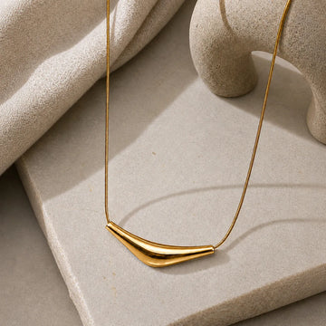 Gold necklace on a textured stone surface
