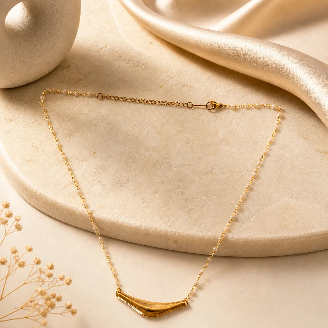 Gold necklace on a beige surface with a soft focus background