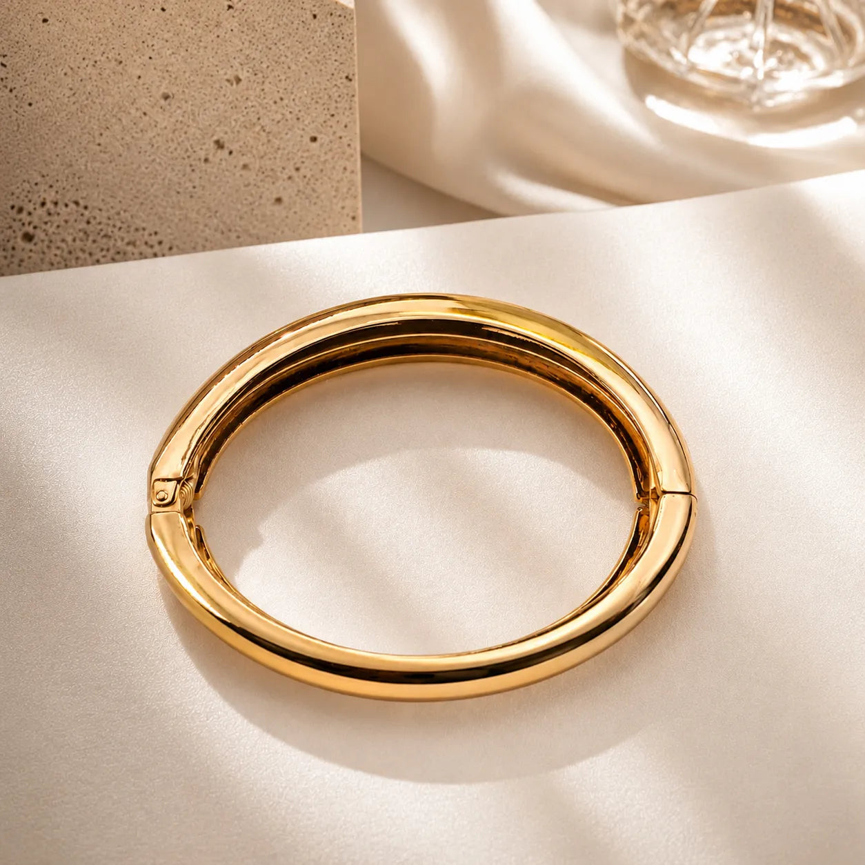 Gold bracelet on a light beige surface with a neutral background