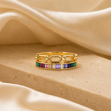 Gold ring with colorful gemstones on a beige fabric background