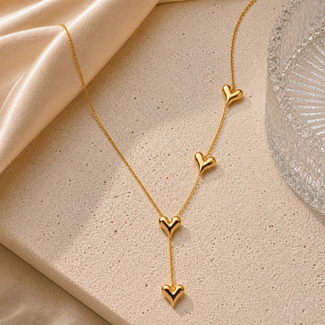 Gold necklace with heart pendants on a beige fabric background