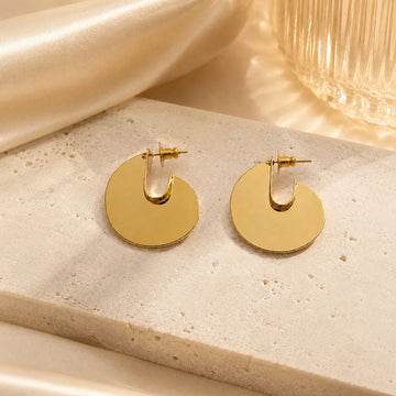 Gold hoop earrings on a textured beige surface