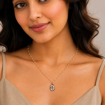 Woman wearing a necklace with a pendant against a neutral background